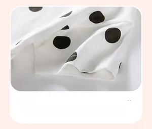 Close-up of girls' cotton sleeve featuring black polka dot print and double-stitched hem