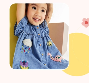 Dettaglio di abito in denim per bambine con ricami colorati di sole, nuvola e dinosauro