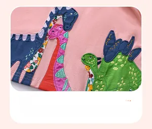 Detail of pink cotton fabric featuring colorful cartoon dinosaur applique embroidery