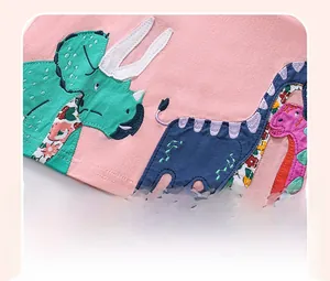 Close-up of colorful dinosaur applique embroidery on pink cotton girl's summer dress