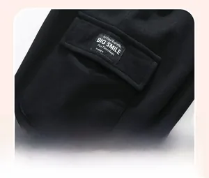 Detail of girls' black cotton pants featuring a cargo pocket with a 'BIG SMILE' woven label