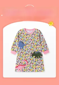 Détail de robe fleurie rose pour enfant avec broderie appliquée de dinosaures colorés