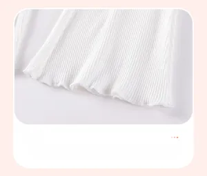 Détail du bas de pantalon en maille côtelée blanche avec bords ondulés et coutures fines