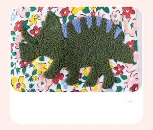 Détail d'une robe fleurie pour enfant avec écusson dinosaure brodé en bouclette