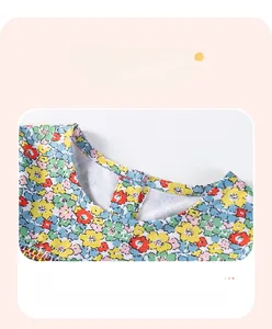 Detail of floral cotton dress neckline with a single red button and smooth piping finish