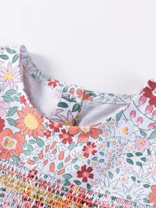Floral cotton girl dress featuring detailed smocking and neckline button closure