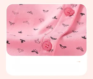Makro-Detail von Mädchen-Baumwollkleid-Stoff mit rosa Kronendruck und Harzknöpfen
