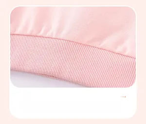 Gros plan sur l'ourlet en maille côtelée rose du sweat pour fille et le tissu élastique