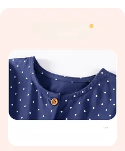 Dettaglio del collo dell'abito blu navy a pois con bottone in legno marrone e pois
