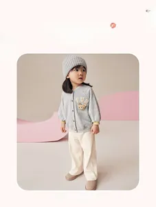 Detail of grey knitted girls' cardigan with bear patch embroidery and soft cotton trousers