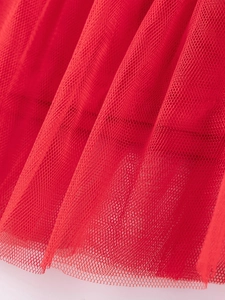 Red multilayered tulle fabric detail showing a fine hexagonal mesh structure and soft pleats