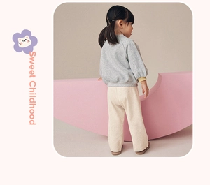 Detail of grey sweatshirt with yellow cuffs and cream waffle knit pants on child
