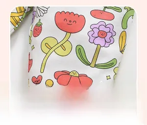 Close-up of soft cotton fabric with colorful cartoon flowers and strawberry prints