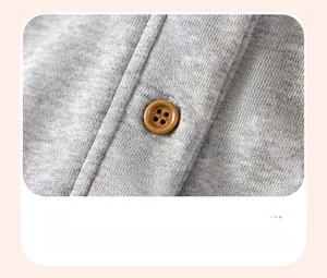 Detail of grey knit fabric with a natural round brown wooden button on children clothing