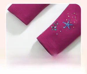 Detail of girl's dark pink knit pants featuring sequined starfish embroidery and dots