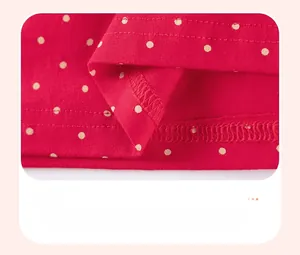 Detailed close-up of double-needle stitching on red polka dot girl's cotton dress hem