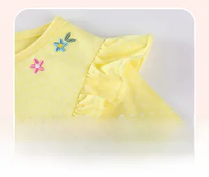 Détail de robe jaune pour enfant à pois blancs avec broderie florale et manches volantées