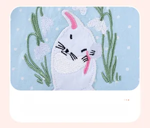 Detail of baby dress featuring cotton blue polka dot fabric and rabbit applique embroidery