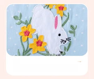Detailed close-up of rabbit and floral embroidery on blue polka dot cotton dress