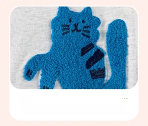 Détail de la broderie bouclée chat bleu sur la robe tricotée grise à manches longues