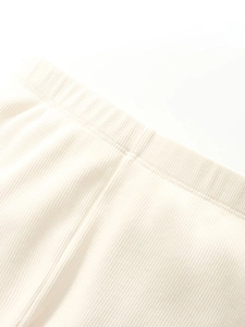 Close-up of cream-colored ribbed knit fabric on toddler sweater with elastic waistband