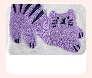 Détail macro de broderie chenille chat violet sur robe tricotée à manches longues