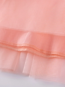 Détail macro du tissu en tulle pêche d'une robe à manches longues et maille de qualité