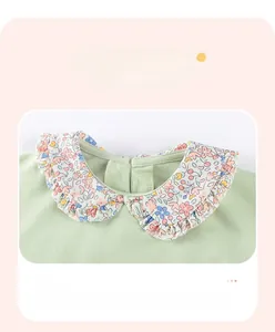 Detailaufnahme des hellgrünen Baby-Strickpullovers mit geblümtem Peter-Pan-Kragen und Rüschen