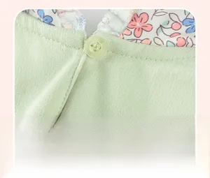 Detailansicht eines hellgrünen Baby-Oberteils mit Rückenknopfverschluss und Blumenbesatz