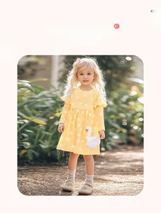 Detail of yellow long-sleeve cotton girls dress with white dots and swan embroidery