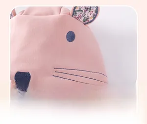 Detail of pink baby hoodie featuring ear flaps with floral lining and embroidered face