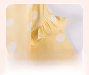 Detail view of cotton ruffles and white polka dots on a yellow baby dress sleeve