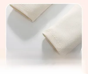 Detailed close-up of ribbed cuffs and fine stitching on a girl's cream knitted sweatshirt