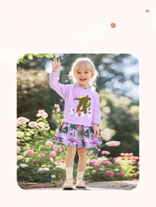 Detail of girls' purple long sleeve dress featuring floral dinosaur patterns in garden