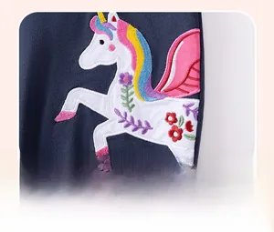 Detailed view of unicorn applique embroidery and floral stitching on navy cotton fabric
