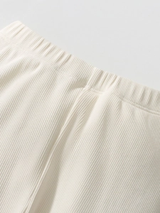 Close-up of cream knit girls' trousers with elastic waistband and vertical rib texture