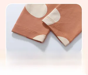 Close-up of terracotta knit cotton trousers with cream polka dots and hem stitching