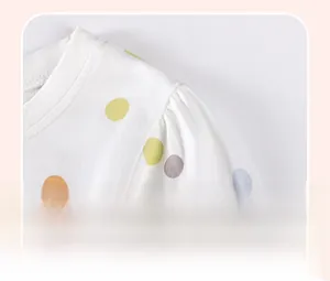 Detail of girl's white cotton dress with colorful polka dots and pleated shoulder design