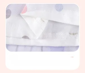 Detail of white cotton dress hem with macaron polka dots and purple mesh tulle layer