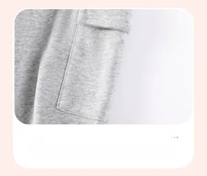 Détail du pantalon en maille grise montrant la poche plaquée latérale avec rabat