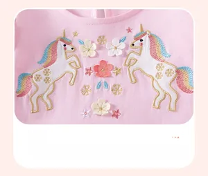 Dettaglio di un abito in cotone rosa con ricamo di unicorno colorato e motivi floreali