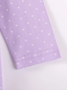 Détail de robe en coton mauve à pois blancs avec coutures soignées sur la manche