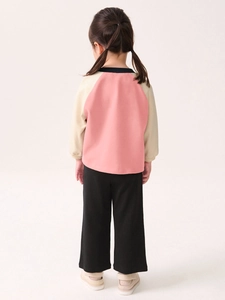 Girl's autumn outfit featuring pink sweatshirt and black wide-leg pants back view
