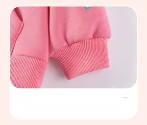 Detail of pink sweatshirt ribbed cuffs with green embroidery and soft thick fabric