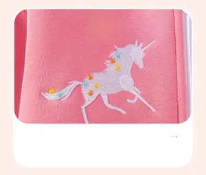 Detail of pink knitted sweater featuring unicorn embroidery with star patterns and blue heart