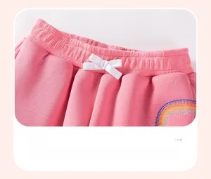 Detail of pink fleece pants featuring elastic waistband with white bow and rainbow embroidery