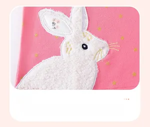 Detailed close-up of pink knit dress with plush rabbit appliqué and gold star embroidery