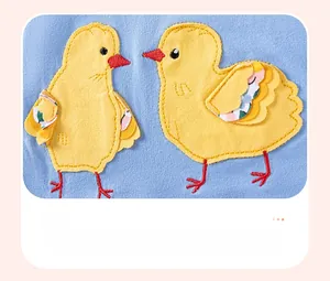 Détail de broderie de deux poussins jaunes sur tissu en coton bleu clair pour filles