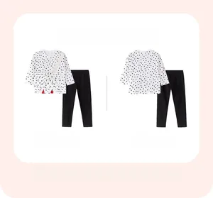 Flat lay of girls long sleeve polka dot shirt and black pants with rainbow patch