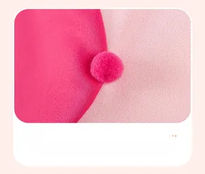 Detailed close-up of pink knitted fabric with soft 3D pompom decorative elements